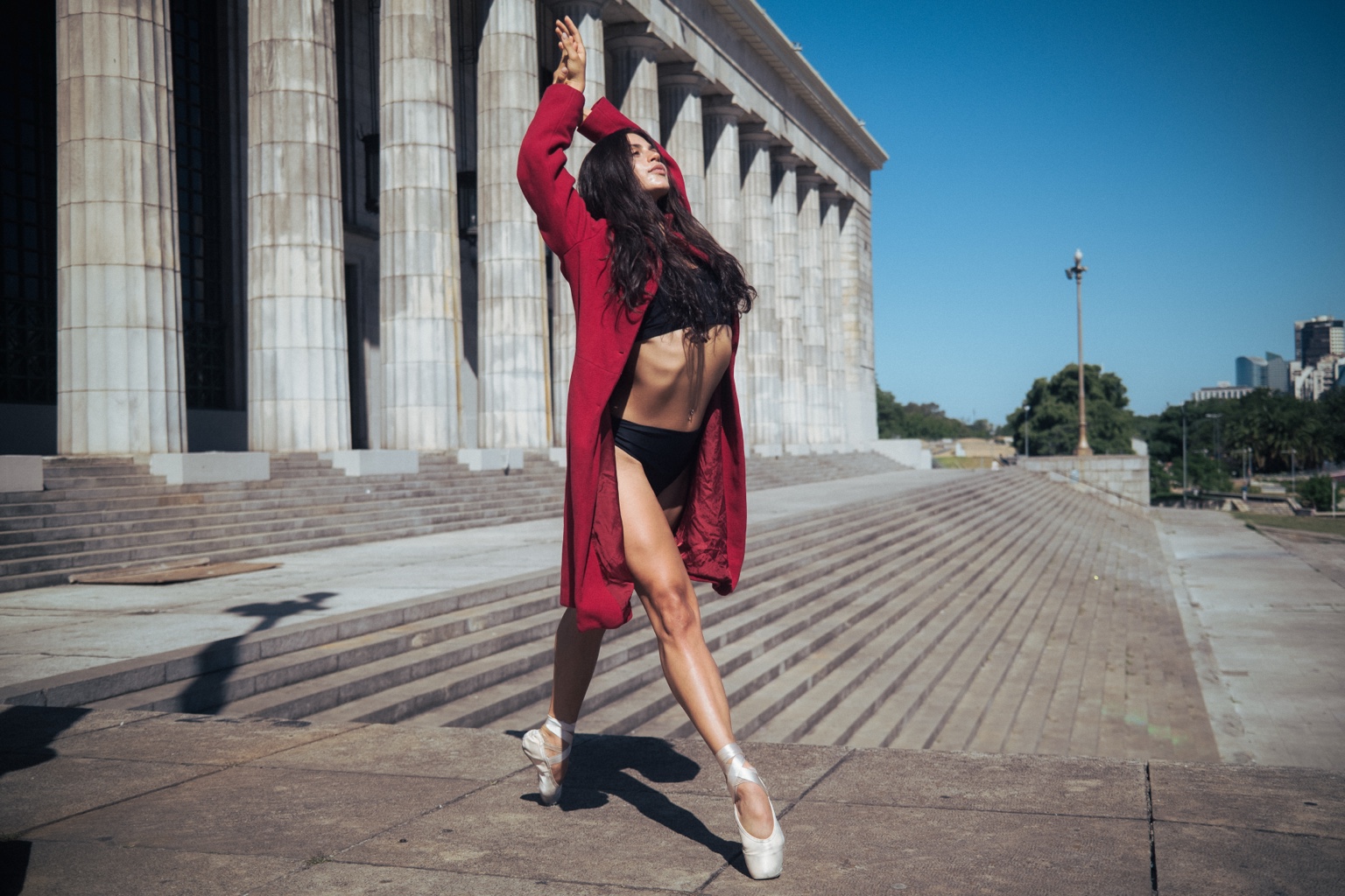 Dancer in red coat in front of columns