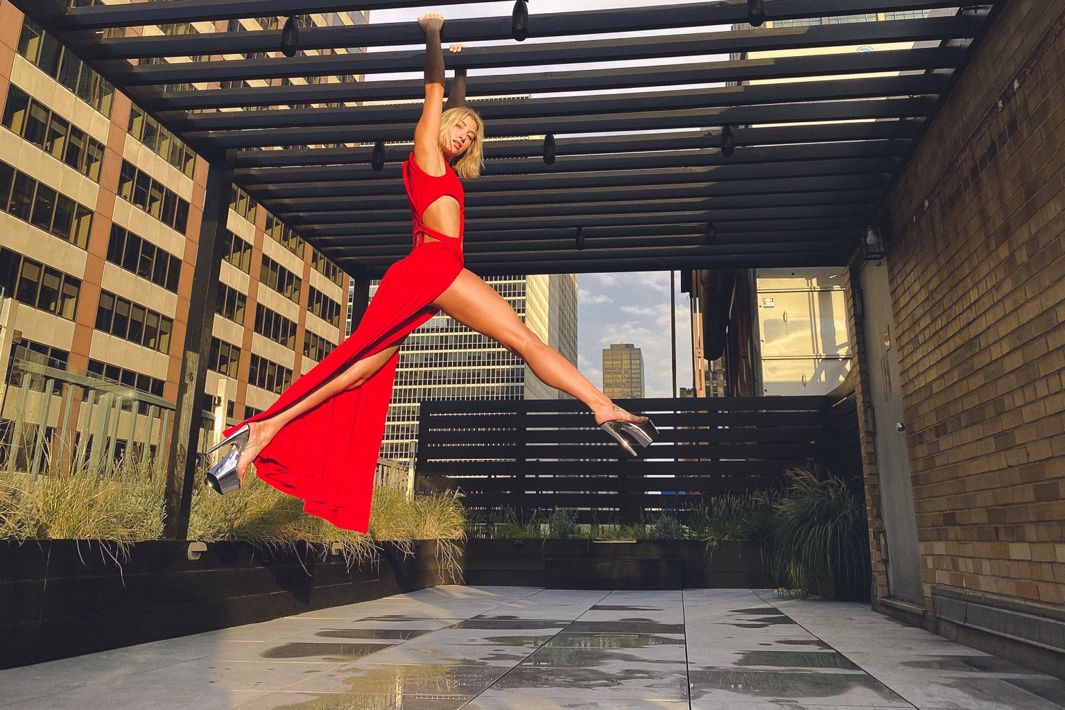 Model in red dress jumping on a rooftop
